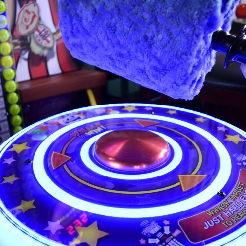 A colorful arcade game with a glowing target and a plush mallet ready for play.