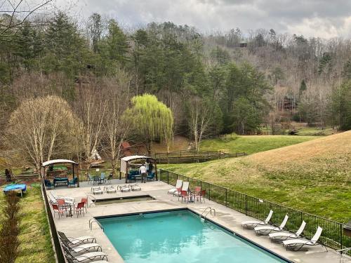 A serene outdoor pool area surrounded by trees and hills, with lounge chairs and shaded cabanas.