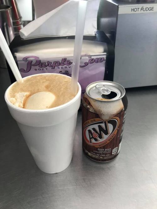 A foam cup with a root beer float and a can of A&W root beer on a counter.