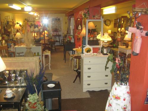 A cozy antique shop filled with furniture, lamps, and decor items in a warm, inviting atmosphere.