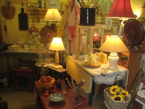 A cozy vintage shop filled with various antiques, lamps, and decorative items on tables and shelves.