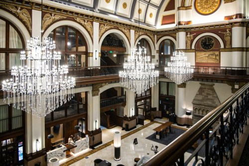 Elegant hotel lobby featuring grand chandeliers, high ceilings, and ornate architectural details.