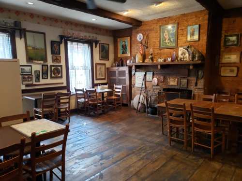 Cozy restaurant interior with wooden tables, chairs, and vintage decor on brick walls, creating a warm atmosphere.