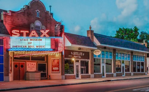 Exterior of the Stax Museum of American Soul Music, featuring a vintage marquee and nearby shops on a sunny day.