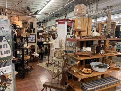 A cozy shop interior filled with vintage decor, furniture, and various home goods displayed on wooden shelves and tables.
