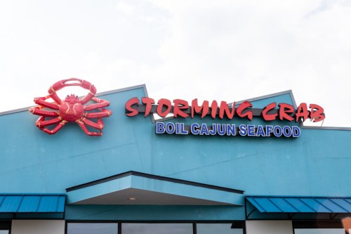 Sign for "Storming Crab" restaurant featuring a large crab graphic and the text "Boil Cajun Seafood" on a blue building.