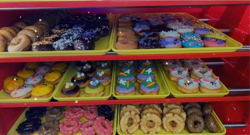 A colorful display of assorted donuts on yellow trays, featuring various toppings and decorations.