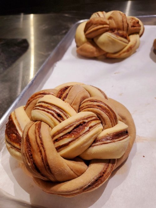 A freshly baked, intricately braided pastry with chocolate swirls on a baking tray.