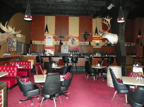 A retro diner with red booths, black chairs, and mounted moose heads on the walls, creating a vintage atmosphere.