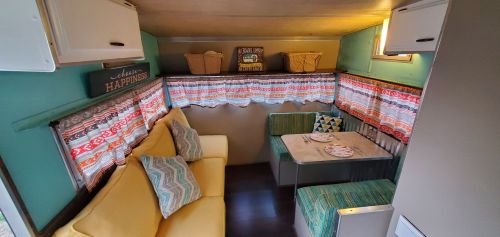 Cozy camper interior with a yellow sofa, patterned curtains, a dining table, and decorative baskets.