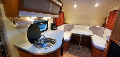 Interior of a cozy camper van featuring a kitchenette, dining area with a table, and comfortable seating.