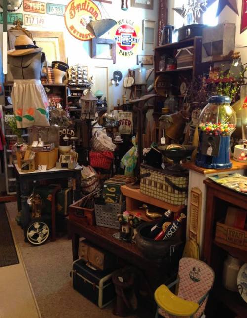 A cluttered vintage shop filled with various antiques, including signs, furniture, and nostalgic items.