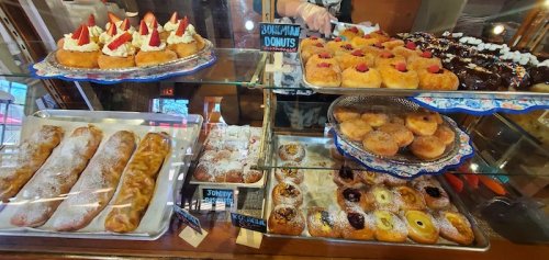 A display case filled with various pastries, including donuts, cream puffs, and fruit-topped desserts.
