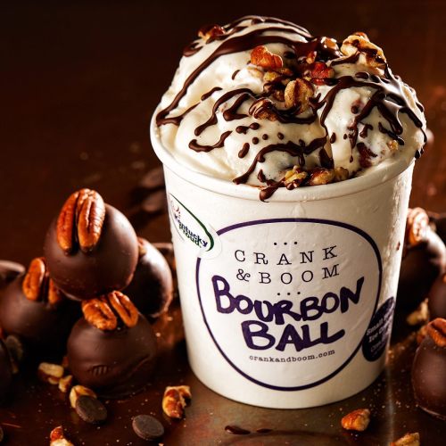 A cup of Bourbon Ball ice cream topped with chocolate drizzle and nuts, alongside chocolate-covered bourbon balls.