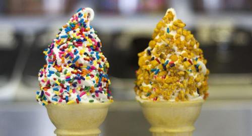 Two ice cream cones: one topped with colorful sprinkles and the other with crushed nuts, both in waffle cones.