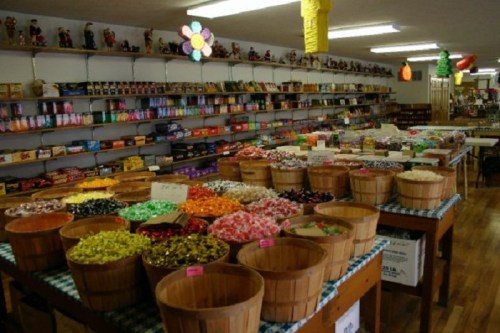 A colorful candy store with baskets of various candies and shelves filled with sweets and toys.