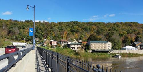 A scenic view of a river, lined with trees in autumn colors, and buildings along the shore under a clear blue sky.