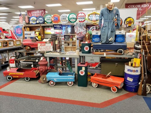 A vintage display featuring colorful toy wagons, retro signs, and nostalgic memorabilia in a shop setting.