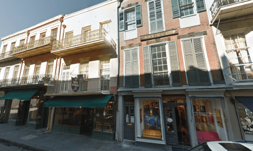 Historic buildings with balconies and shopfronts in a vibrant street, showcasing a mix of architecture and storefronts.