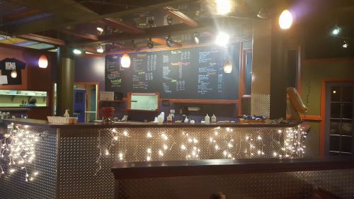 Cozy café interior with a menu board, illuminated by warm lights and decorated with string lights along the counter.