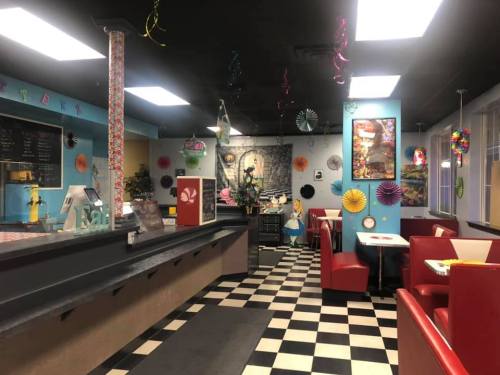 Colorful diner interior with checkered floor, red booths, and festive decorations on the walls and ceiling.