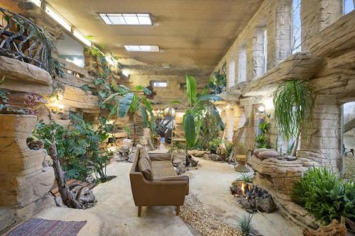 A unique indoor space with rock-like walls, lush plants, and a cozy seating area, resembling a natural cave environment.