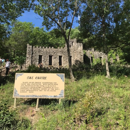 A stone structure resembling a castle, surrounded by trees, with a sign reading "The Castle" in the foreground.