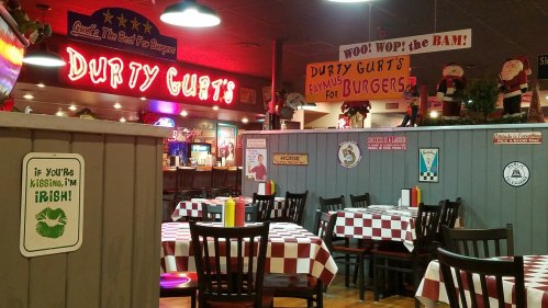 Interior of a lively restaurant with checkered tables, colorful signs, and festive decorations.