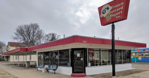 Exterior of G's Frozen Custard and Yogurt, featuring a red awning, large windows, and an "Open" sign.