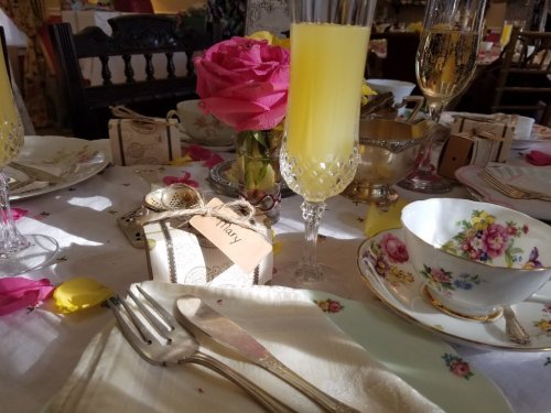 A beautifully set table with floral decorations, champagne glasses, and a pink rose centerpiece.