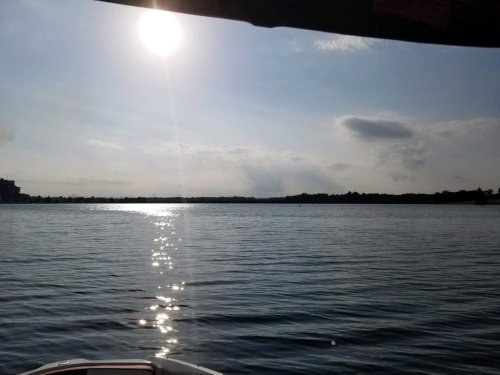 A serene lake scene with sunlight reflecting on the water, under a partly cloudy sky.