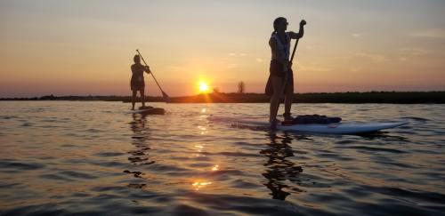 Two people paddleboarding at sunset, with vibrant colors reflecting on the water's surface.