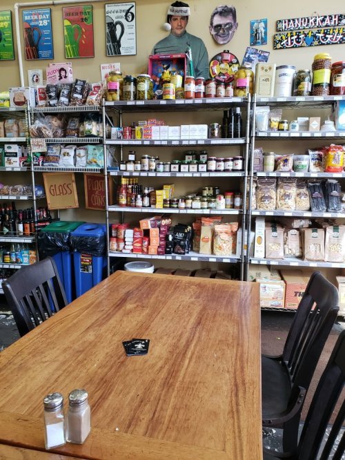 A wooden table in a store with shelves filled with various food products and condiments in the background.