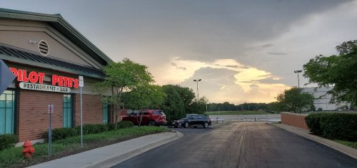 Exterior of Pilot Pete's Restaurant & Bar at sunset, with a cloudy sky and parked cars in the foreground.