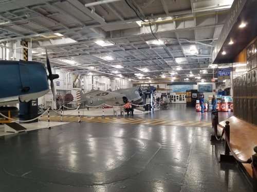 Interior of a museum featuring vintage aircraft, with a polished floor and informational displays in the background.