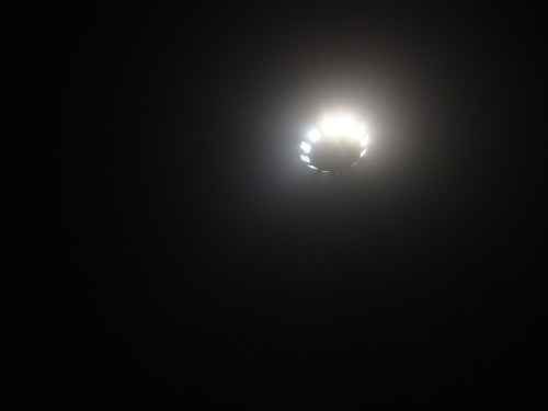A bright light source shines in a dark environment, creating a halo effect around it.
