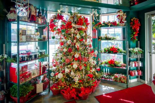 A festive shop display featuring a decorated Christmas tree surrounded by holiday decorations and gifts.