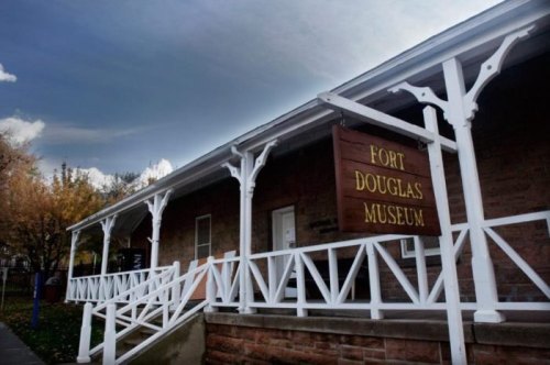 Exterior view of the Fort Douglas Museum, featuring a wooden sign and a porch with white railings.