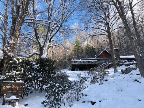 A snowy landscape featuring a rustic cabin surrounded by trees and a sign for "Entrance" to a nature center.