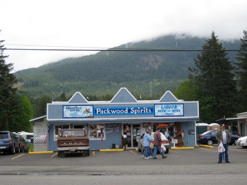 A liquor store named "Packwood Spirits" with mountains in the background and people walking outside.