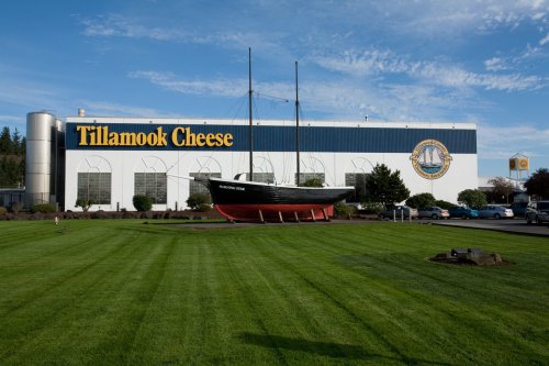 Exterior of Tillamook Cheese factory with a large boat sculpture in front and a well-maintained lawn.