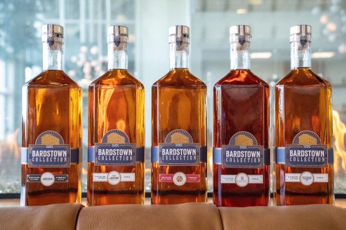 Five bottles of Bardstown Collection whiskey lined up on a table, showcasing various labels and amber hues.