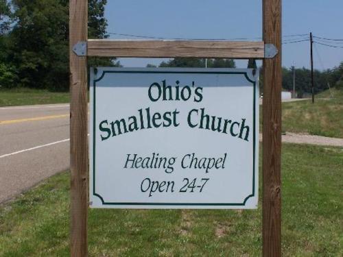 Sign for "Ohio's Smallest Church," labeled as a Healing Chapel, open 24/7, located by a roadside.