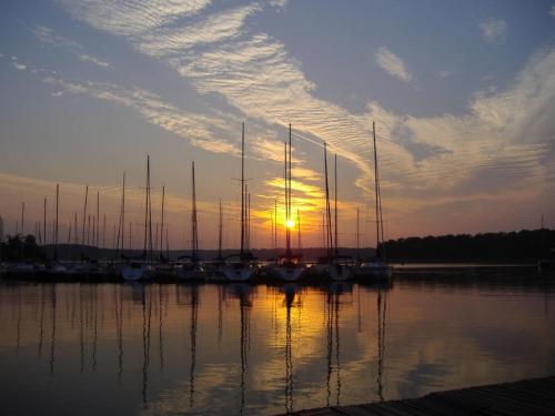 Sunset over a calm lake with sailboats silhouetted against the colorful sky and reflections on the water.