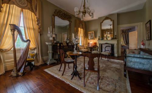 Elegant vintage living room with a harp, ornate mirrors, and warm lighting, featuring rich wood floors and classic decor.