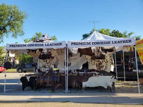 A market stall featuring premium cowhide leather products, with hides displayed and various leather goods for sale.