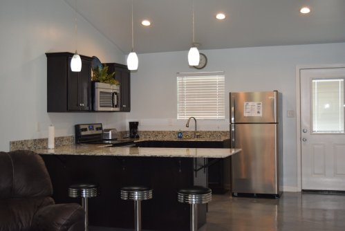 Modern kitchen with dark cabinets, stainless steel appliances, granite countertops, and bar seating. Bright and spacious.