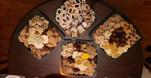 Four trays filled with an assortment of cookies and sweets, including chocolate, fruit, and decorative treats.