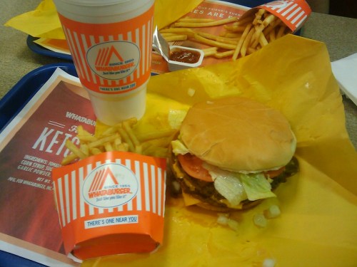 A tray with a Whataburger meal featuring a burger, fries, and a drink, all in branded packaging.