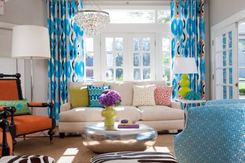 Bright living room with colorful curtains, a white sofa, vibrant cushions, and a stylish coffee table.